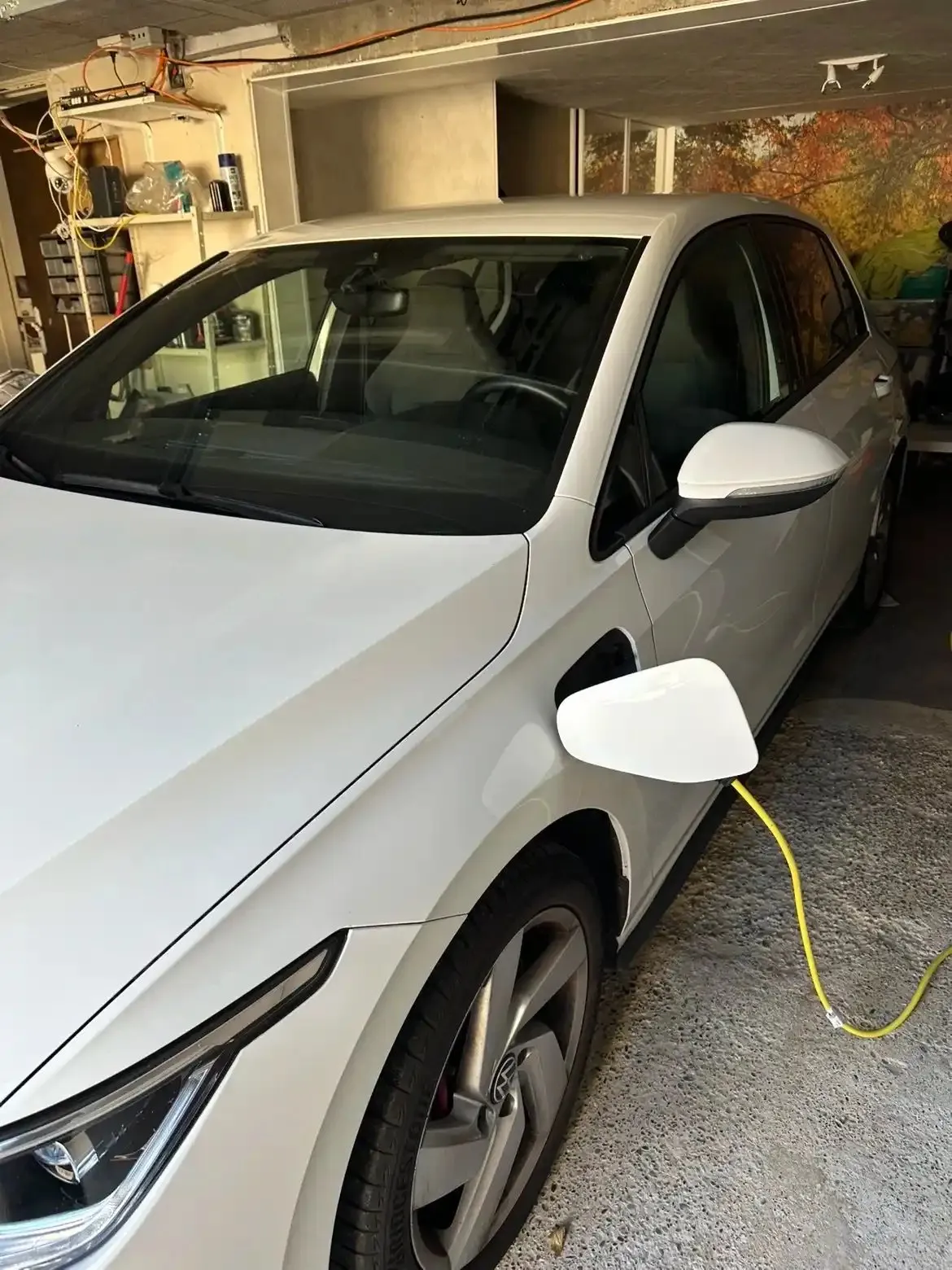 Voiture électrique blanche branchée à une borne de recharge dans un garage
