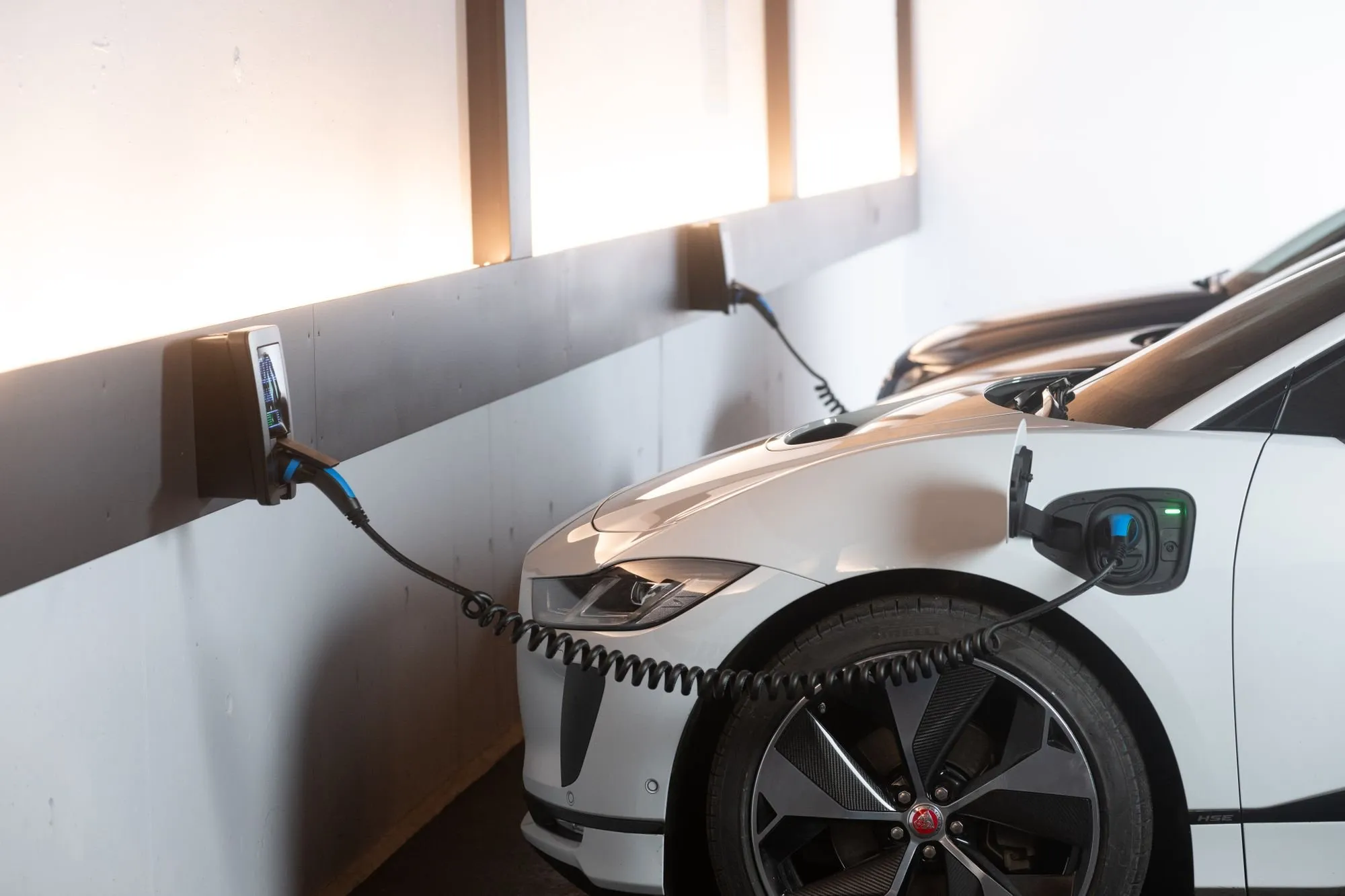 Voiture électrique en charge sur une borne murale dans un parking