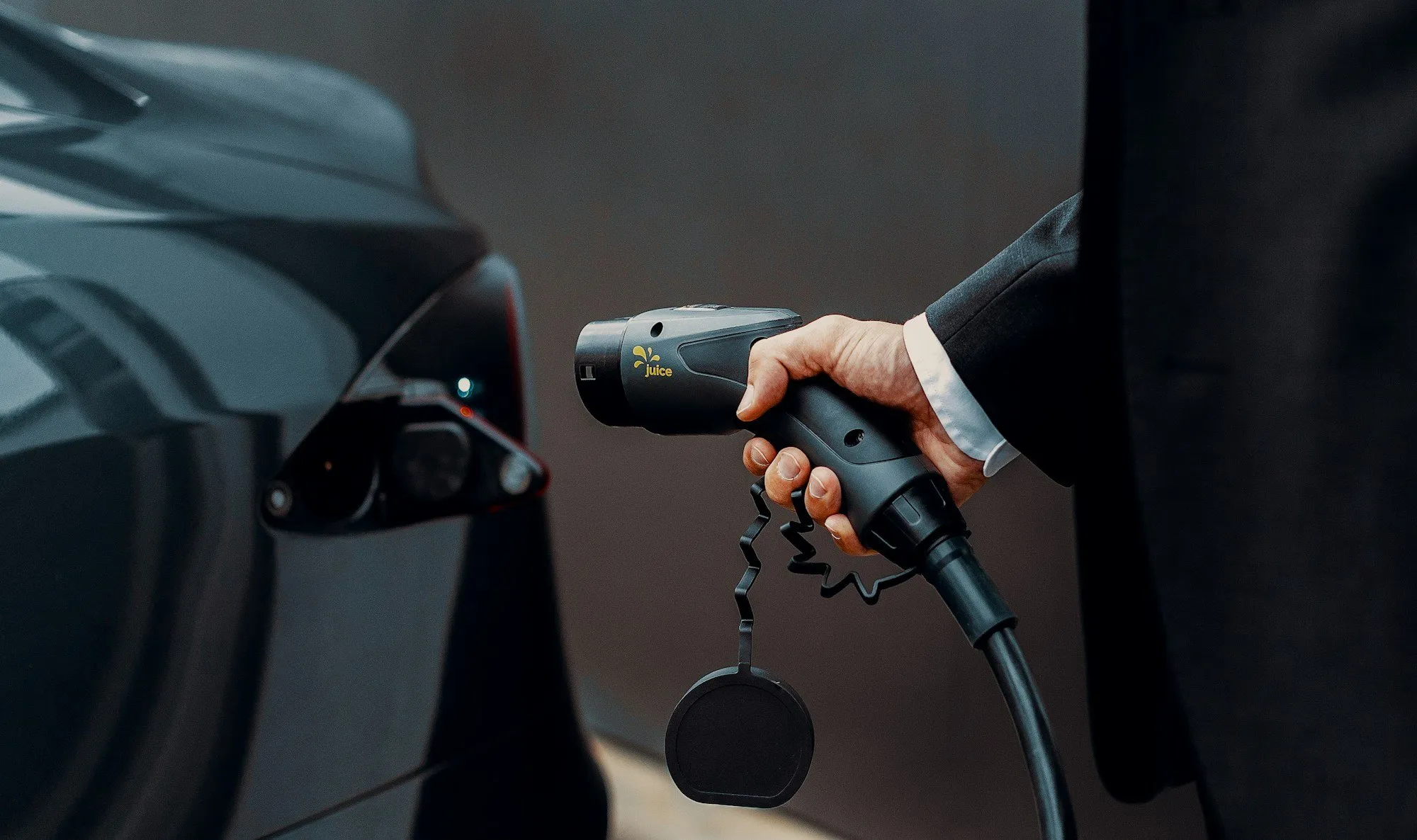 Homme en costume branchant le câble de recharge sur une voiture électrique